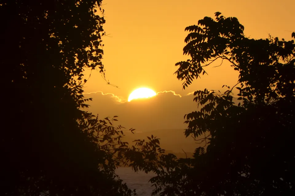 Sol nascendo atrás da silhueta das árvores, visto de Morro de São Paulo