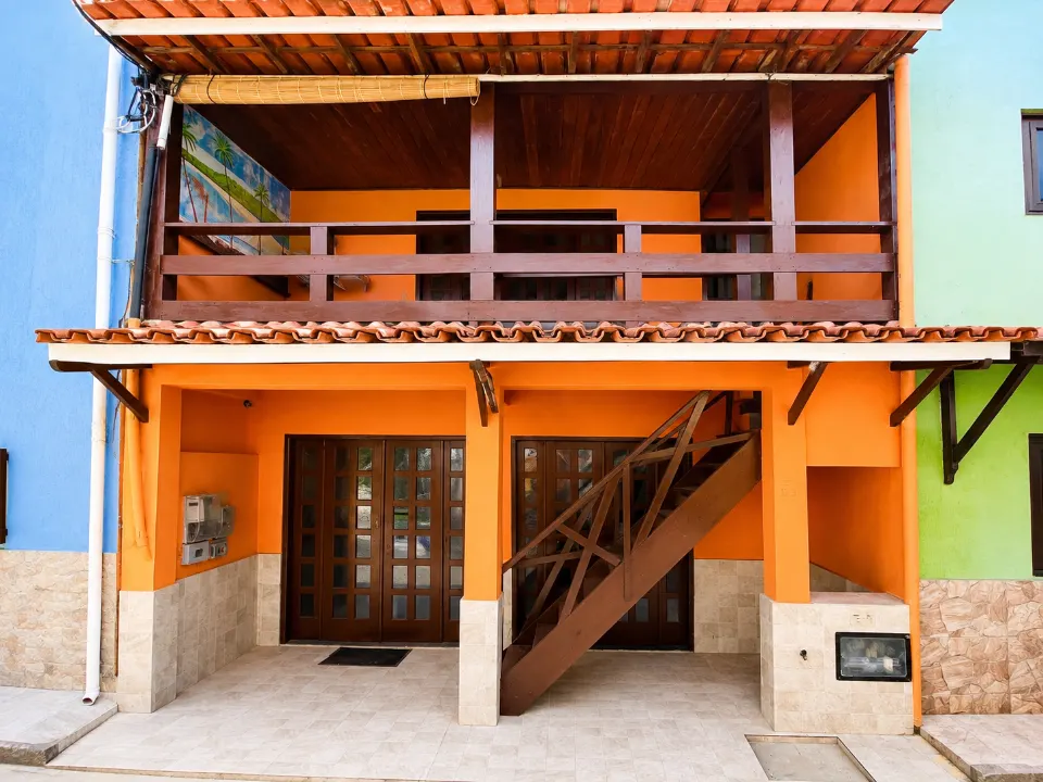 Fachada laranja da Pousada Vila Nova, com varandas e escada de madeira